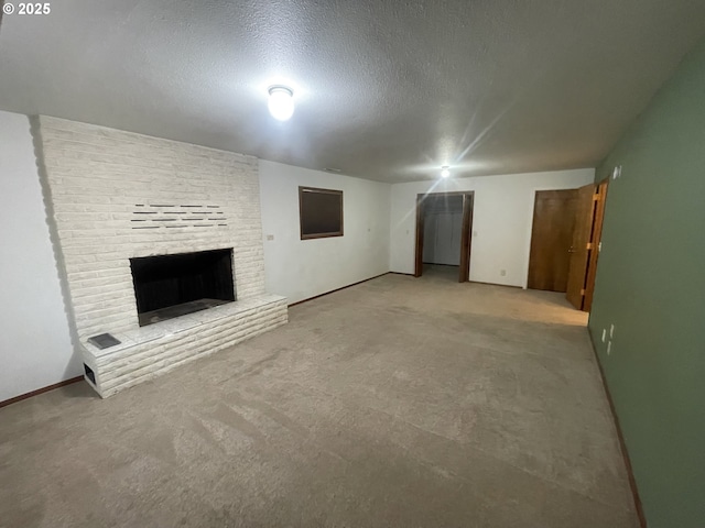 unfurnished living room featuring a brick fireplace, light colored carpet, and a textured ceiling