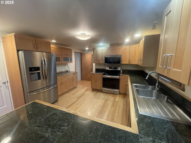 kitchen with stainless steel appliances, sink, and light hardwood / wood-style flooring