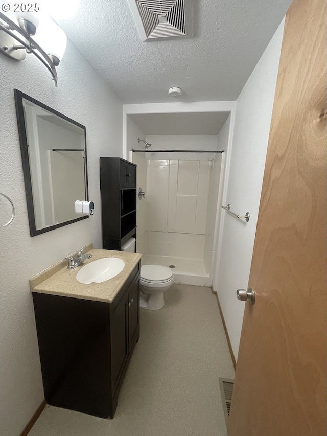 bathroom featuring walk in shower, vanity, toilet, and a textured ceiling