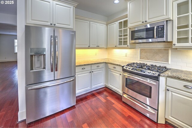 619 SW Foresta Ter, Portland, OR 97225 - kitchen with stainless steel appliances, dark wood-style floors, glass insert cabinets, light stone counters, and recessed lighting