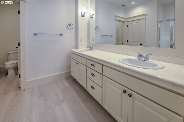 619 SW Foresta Ter, Portland, OR 97225 - bathroom with wood finished floors, baseboards, double vanity, toilet, and recessed lighting