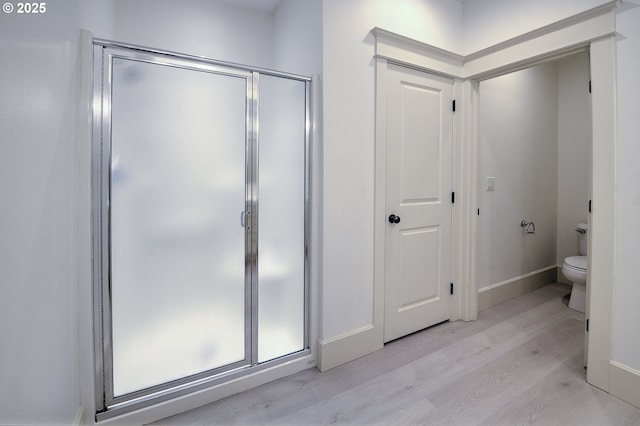 619 SW Foresta Ter, Portland, OR 97225 - bathroom with wood finished floors, a stall shower, toilet, and baseboards