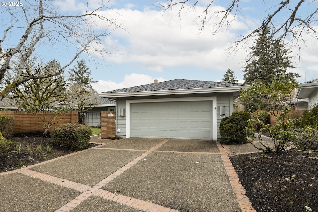 single story home with brick siding, a shingled roof, an attached garage, fence, and driveway