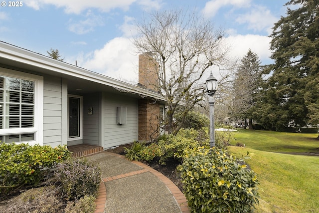 entrance to property with a yard and a chimney