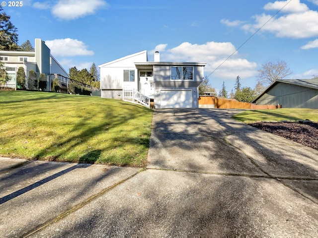 view of front of property with a chimney, concrete driveway, an attached garage, a front yard, and fence