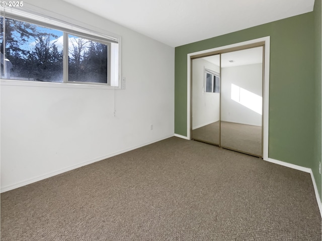 unfurnished bedroom with a closet, baseboards, and carpet flooring