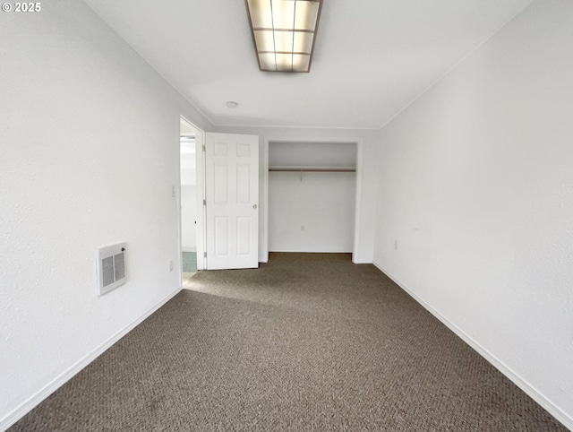 unfurnished bedroom with baseboards, visible vents, dark colored carpet, and a closet