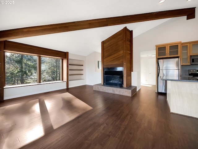 unfurnished living room with dark wood finished floors, visible vents, lofted ceiling with beams, a tiled fireplace, and baseboards