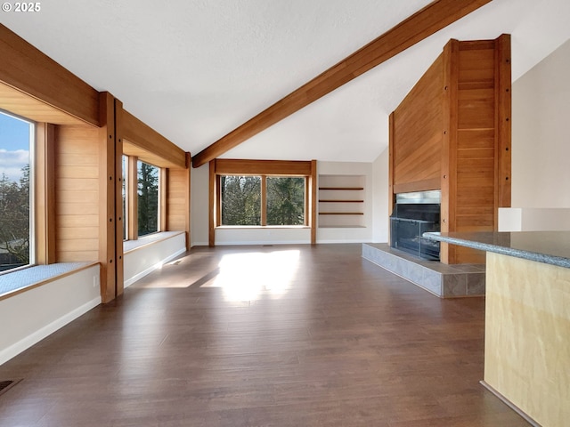 unfurnished living room with lofted ceiling with beams, a fireplace, built in features, baseboards, and dark wood finished floors