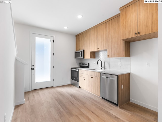 kitchen with backsplash, sink, light hardwood / wood-style flooring, and appliances with stainless steel finishes