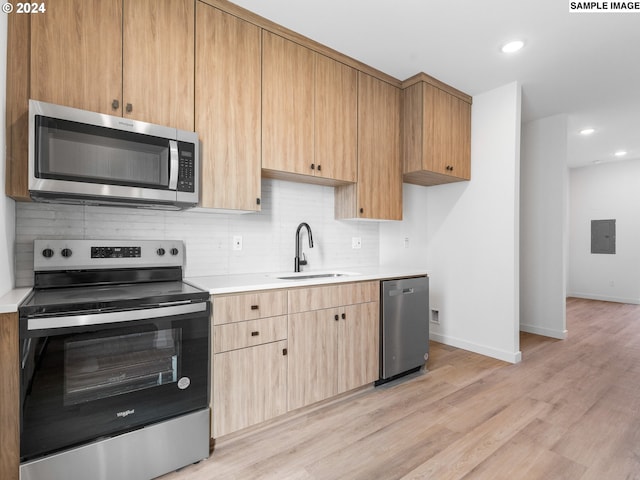 kitchen featuring sink, stainless steel appliances, light hardwood / wood-style flooring, backsplash, and electric panel