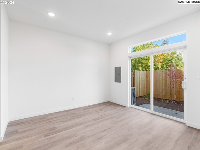 empty room featuring electric panel and light hardwood / wood-style floors