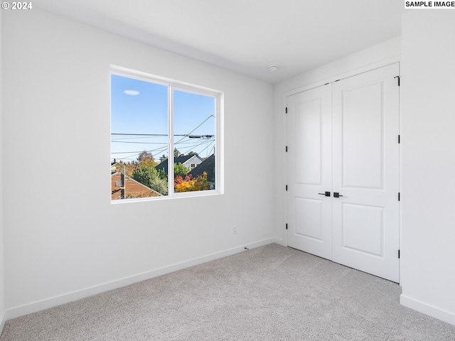 unfurnished bedroom with light carpet and a closet