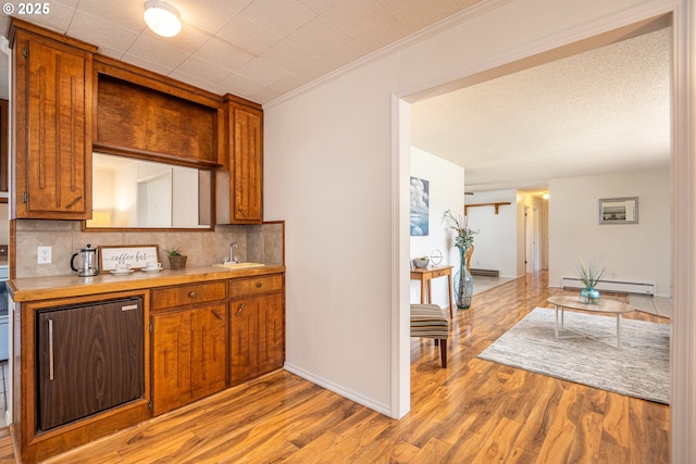 42 Sooter Rd, Underwood, WA 98651 - kitchen with a baseboard heating unit, decorative backsplash, light wood-type flooring, brown cabinetry, and light countertops