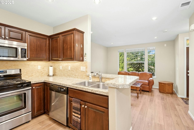 15971 NW Hildago Ln, Portland, OR 97229 - kitchen featuring appliances with stainless steel finishes, light countertops, light wood finished floors, backsplash, and a peninsula