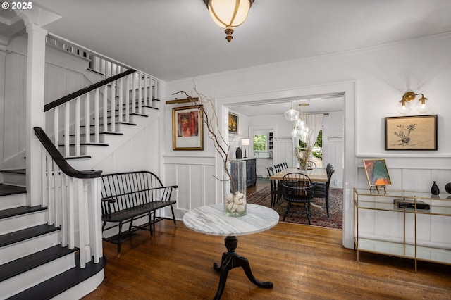 interior space with a decorative wall, stairway, crown molding, and wood finished floors