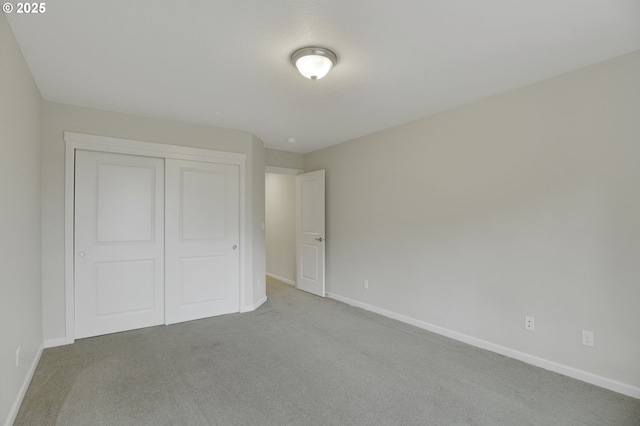unfurnished bedroom featuring carpet, baseboards, and a closet