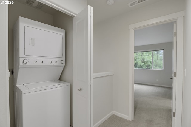 washroom featuring stacked washing machine and dryer, light carpet, and baseboards