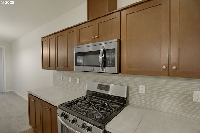 kitchen with stainless steel appliances, light countertops, tasteful backsplash, and brown cabinetry