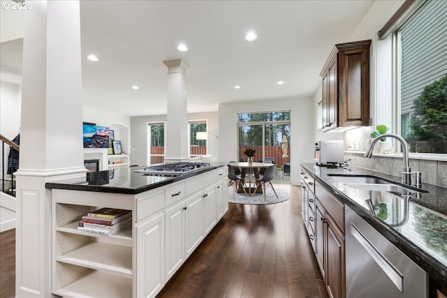 kitchen with white cabinets, a center island, stainless steel appliances, open shelves, and a sink