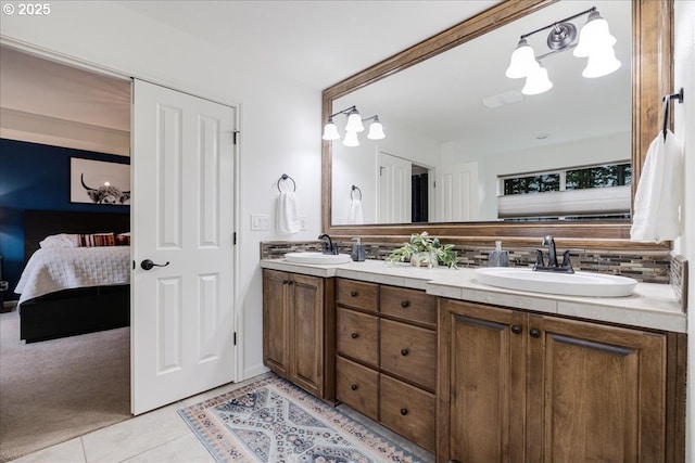 full bath featuring ensuite bathroom, double vanity, a sink, and tile patterned floors