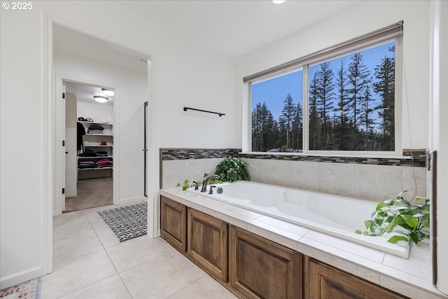 bathroom featuring a spacious closet, a garden tub, and tile patterned floors