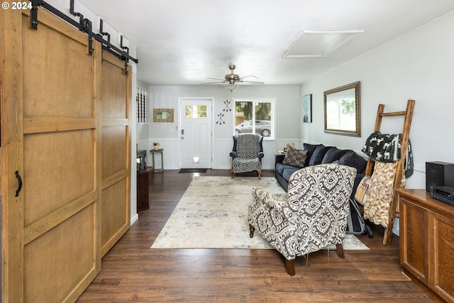 living room with ceiling fan, a barn door, and dark hardwood / wood-style floors