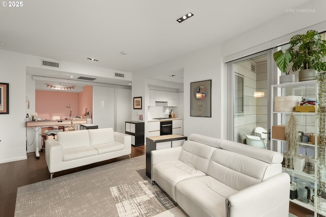 living area with visible vents, baseboards, and wood finished floors