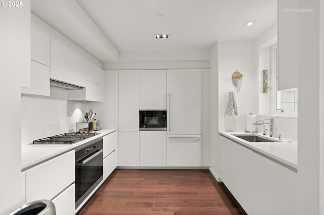 kitchen featuring dark wood finished floors, light countertops, white cabinetry, a sink, and black appliances