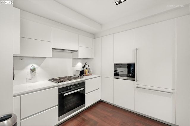 kitchen featuring black microwave, wall oven, dark wood-style flooring, light countertops, and stainless steel gas stovetop