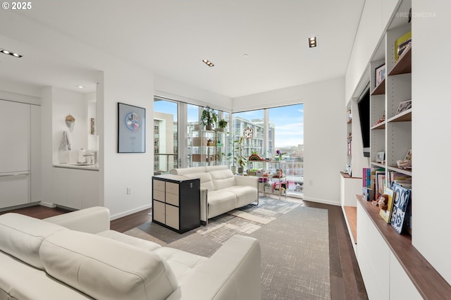 living room with a city view, recessed lighting, wood finished floors, and baseboards