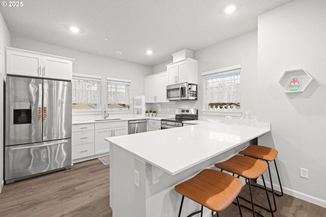 kitchen featuring kitchen peninsula, stainless steel appliances, and white cabinetry