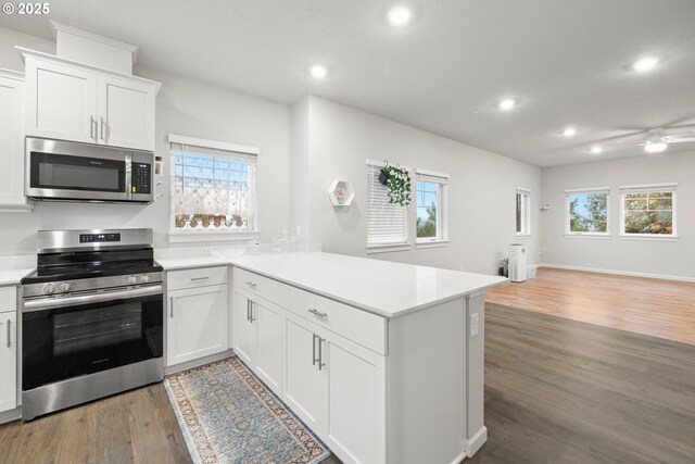 kitchen featuring dark hardwood / wood-style floors, white cabinetry, kitchen peninsula, and appliances with stainless steel finishes