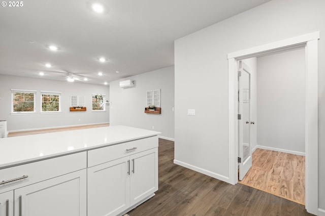 kitchen featuring white cabinets, dark hardwood / wood-style floors, ceiling fan, and a wall unit AC