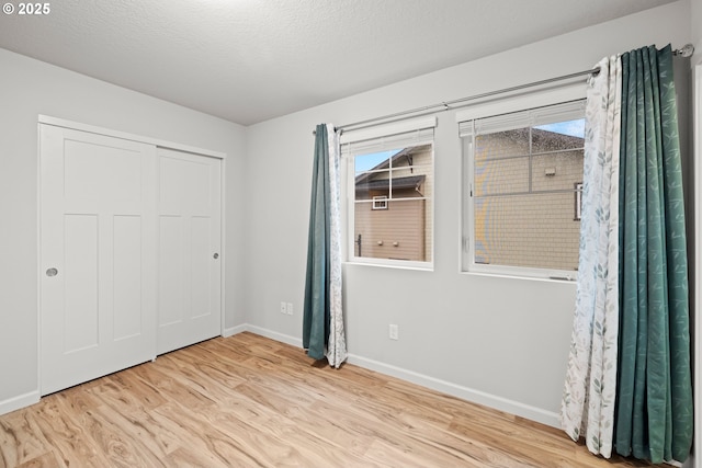 unfurnished bedroom featuring a textured ceiling, light hardwood / wood-style flooring, and a closet