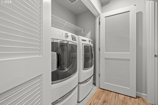 clothes washing area featuring separate washer and dryer and light hardwood / wood-style flooring