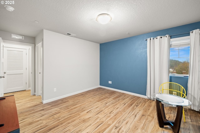 unfurnished room with light hardwood / wood-style flooring and a textured ceiling