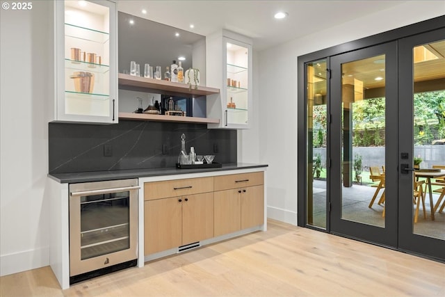 bar with light brown cabinetry, light hardwood / wood-style floors, decorative backsplash, and wine cooler