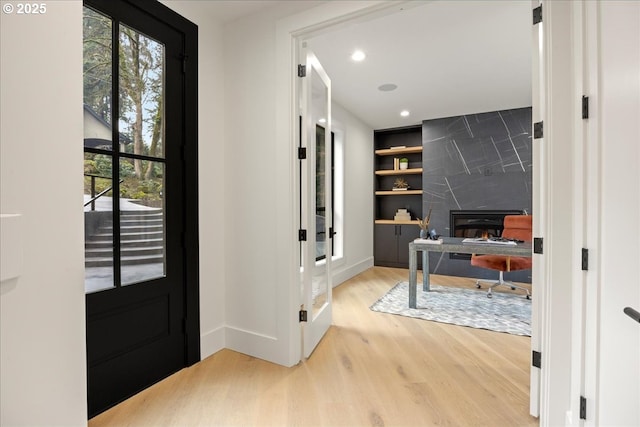 entrance foyer with a high end fireplace, light wood-type flooring, and plenty of natural light