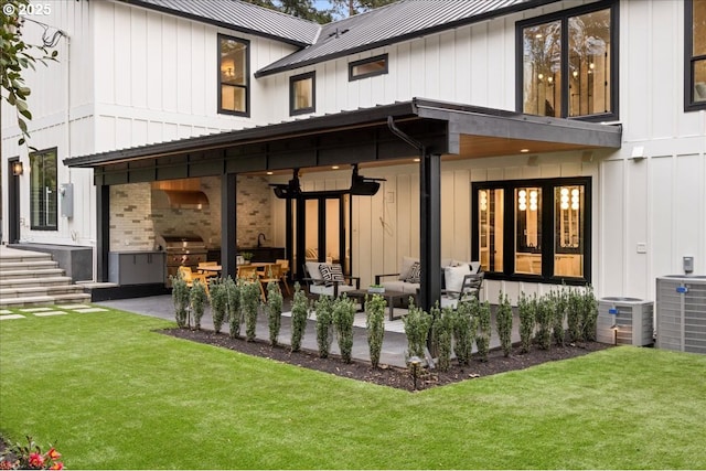 rear view of property featuring exterior kitchen, a patio area, outdoor lounge area, and a yard