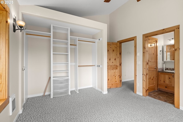 unfurnished bedroom featuring carpet floors, baseboards, ensuite bathroom, and vaulted ceiling