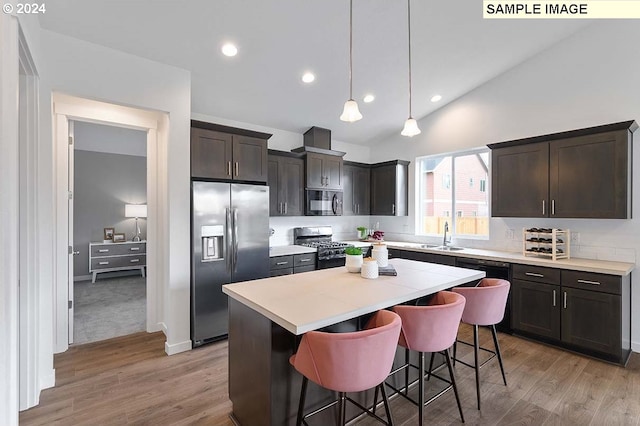 kitchen with appliances with stainless steel finishes, a center island, light countertops, light wood finished floors, and a breakfast bar area