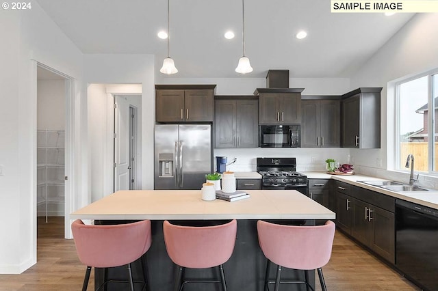 kitchen with black appliances, a sink, a center island, a breakfast bar area, and recessed lighting