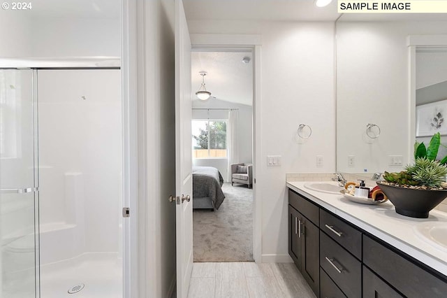 bathroom featuring a shower stall, double vanity, ensuite bathroom, and baseboards