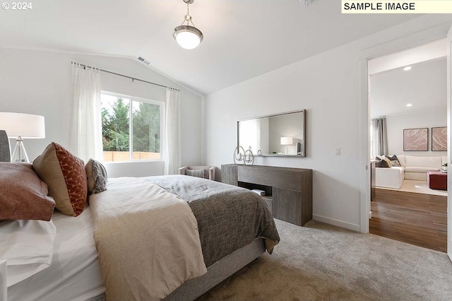carpeted bedroom with vaulted ceiling and baseboards