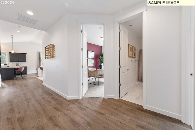 hallway featuring wood finished floors, healthy amount of natural light, lofted ceiling, an office area, and baseboards