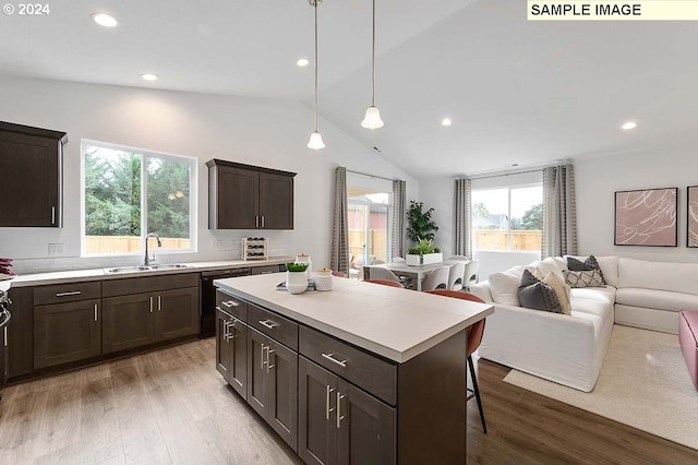 kitchen featuring lofted ceiling, a sink, wood finished floors, dark brown cabinets, and light countertops