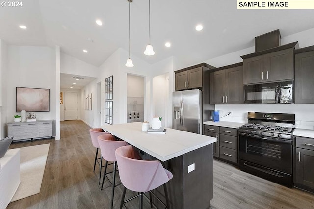 kitchen with black appliances, lofted ceiling, a kitchen island, light countertops, and a breakfast bar