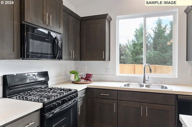 kitchen featuring black appliances, a sink, dark brown cabinetry, and healthy amount of natural light