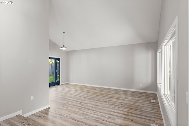 spare room with baseboards, light wood-type flooring, and high vaulted ceiling
